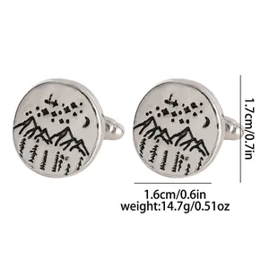 Macro shot of silver round cufflinks featuring laser-etched mountain and moon nature scenery