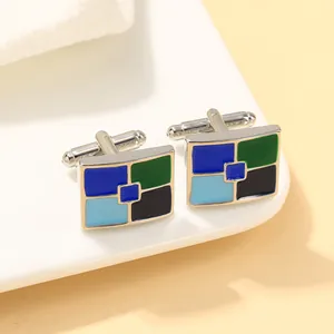 Macro-opname van zilveren vierkante manchetknopen met blauw en groen emaille patroon