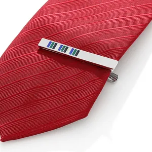 Close-up of a polished silver men's tie clip with colorful stripes on a red striped tie