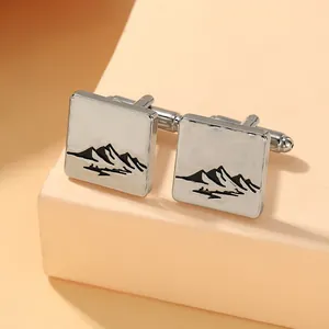 Detailed view of silver square cufflinks with black engraved mountain scenery pattern