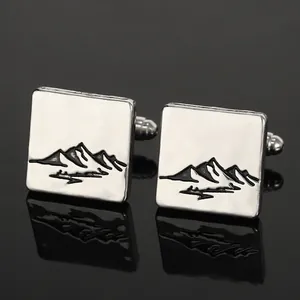 Macro detail of silver square cufflinks featuring black mountain texture on mirror background