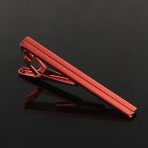 Macro shot of a modern bright red metallic tie clip on a sleek black reflective surface