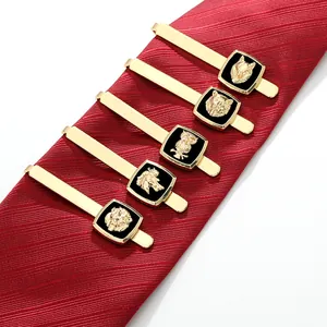 Detalle de pasadores de corbata dorados con relieves de animales en corbata de seda roja