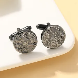 Classic round gunmetal cufflinks with hammered texture on a minimalist white stand