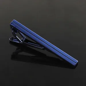 Close-up of sleek dark blue metallic tie clip with vertical groove on reflective surface