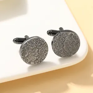 Macro shot of gun-black round cufflinks with a hammered lunar surface texture for business