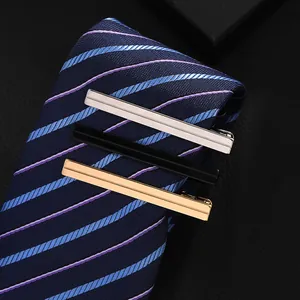 Detailed close-up of three metallic tie clips in silver, black, and gold on a blue tie