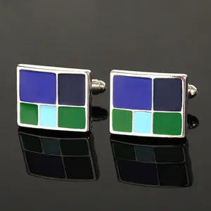 Macro-opname van zilveren manchetknopen met blauw en groen emailpatroon op zwart oppervlak