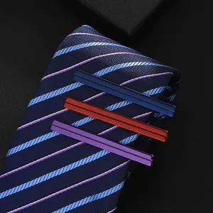 Detailed close-up of textured metal tie clips on a striped navy necktie in a gift box