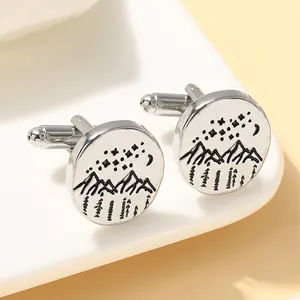 Detailed shot of round mountain and moon cufflinks on a white display stand