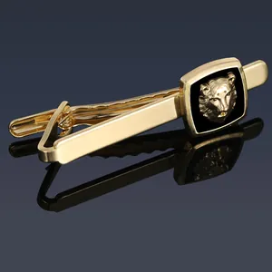 Macro shot of gold-plated tie clip with embossed lion head on blue mirror background
