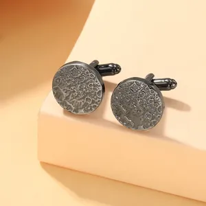 Detailed close-up of gunmetal round cufflinks with unique hammered crater texture