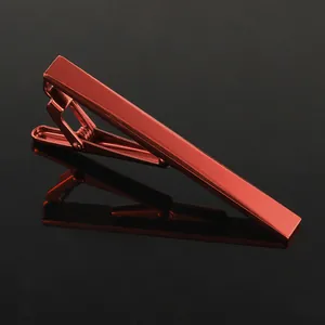 Detailed close-up of a polished red metallic tie clip on a black reflective surface