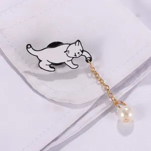 Gros plan d'une broche chat blanc avec chaîne dorée et perle sur un col de chemise