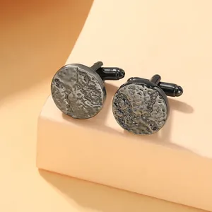 Macro shot of gun black round cufflinks with rock texture on a minimal pedestal