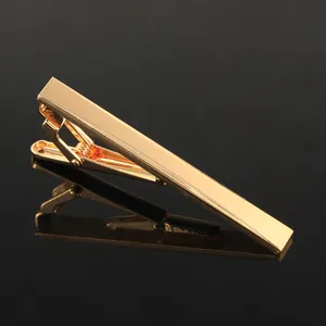 Macro view of polished gold tie clip with mirror finish and spring clamp mechanism