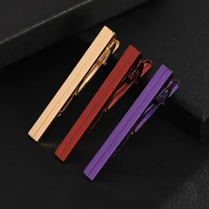 Detailed view of silver, red, and purple metallic tie clips with textured stripes