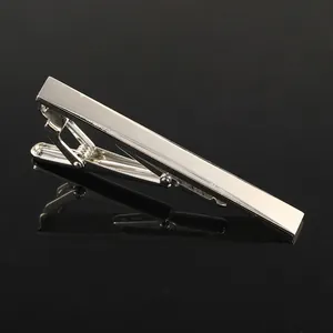 Detailed view of polished silver metal tie clip with sawtooth grip on black surface