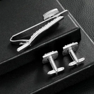 Silver cufflinks and tie clip set with grid texture on a black leather gift box