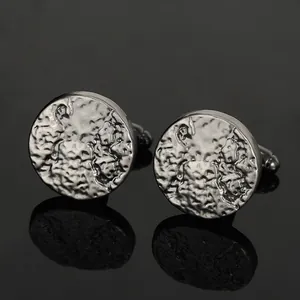 Macro view of gunmetal round cufflinks featuring a hammered rock texture on black reflective surface
