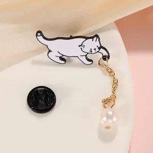 Détail macro d'une jolie broche chat noir et blanc avec chaîne dorée et perle pendante
