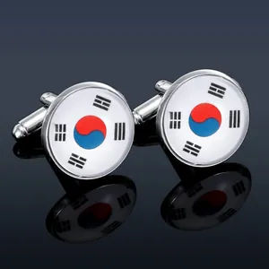 Macro shot of silver metal cufflinks with South Korean flag design on dark background