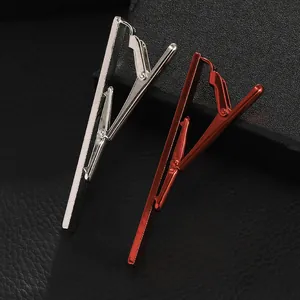 Detail of silver and red metallic tie clips for men set against a black leather background