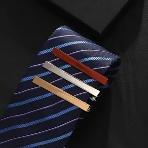 Detailed view of gold, silver, and bronze tie clips on a navy striped necktie