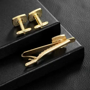 Business men's set featuring gold square cufflinks and matching tie clip on black leather