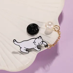 Détail de la broche chat en émail avec chaîne dorée et perle blanche sur plateau