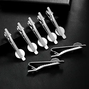 Set of silver tie clips with round flat base on black leather background