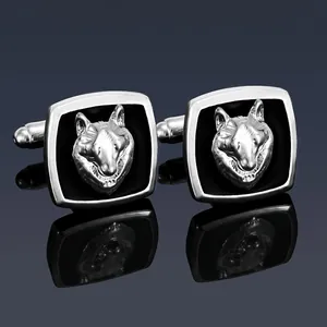 Detailed close-up of silver wolf head cufflinks with black enamel on a mirror background