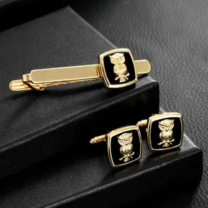 Business suit set featuring golden owl cufflinks and tie clip on black leather stand