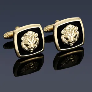 Detailed view of square gold lion head cufflinks with black enamel on a reflective surface