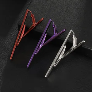 Three premium metal tie clips in red, purple, and silver on black leather surface