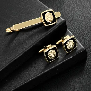 Men's gold lion head cufflinks and tie clip set on black leather display base