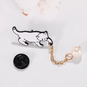 Détail de la broche chat en émail blanc avec chaîne dorée, perle d'imitation et fermoir