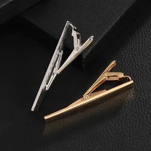 Close-up of polished gold and silver necktie clips on elegant black textured background