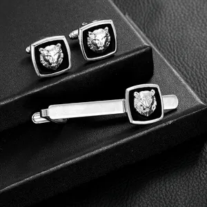 Silver lion head cufflinks and tie clip set on a black textured background for men