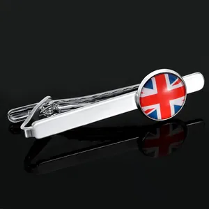 Close-up of a silver tie clip featuring a circular British flag badge on a black background