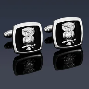 Macro shot of silver owl cufflinks with black inlay and detailed feather textures