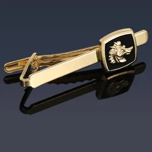 Macro shot of gold tie clip with black enamel wolf head emblem on reflective surface