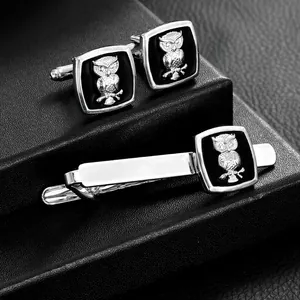 Polished silver owl cufflink and tie clip set on a black premium display base
