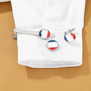 Detailed view of French flag cufflinks worn on a white shirt cuff with a leather backdrop