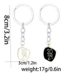Set of 2024 graduation keychains in gold finish with black and white enamel pendants