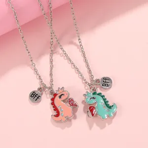 Close-up of BFF necklaces featuring colorful cartoon dinosaur pendants with crown and heart