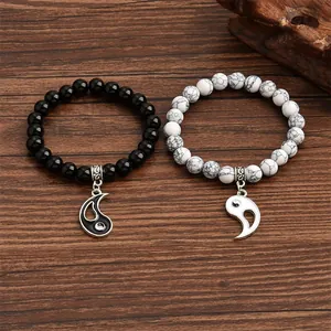 Close-up of Yin Yang couple bracelets with black and white marble beads on wood