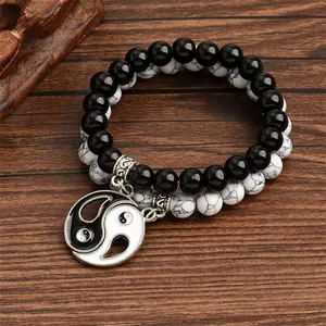 Close-up of Yin Yang Tai Chi charm on double-layer beaded bracelets over wood