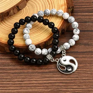 Detailed close-up of Yin Yang charm bracelets with black and white beads on wood