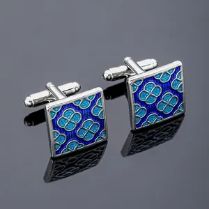 Gros plan de boutons de manchette carrés en métal avec motif floral en émail bleu